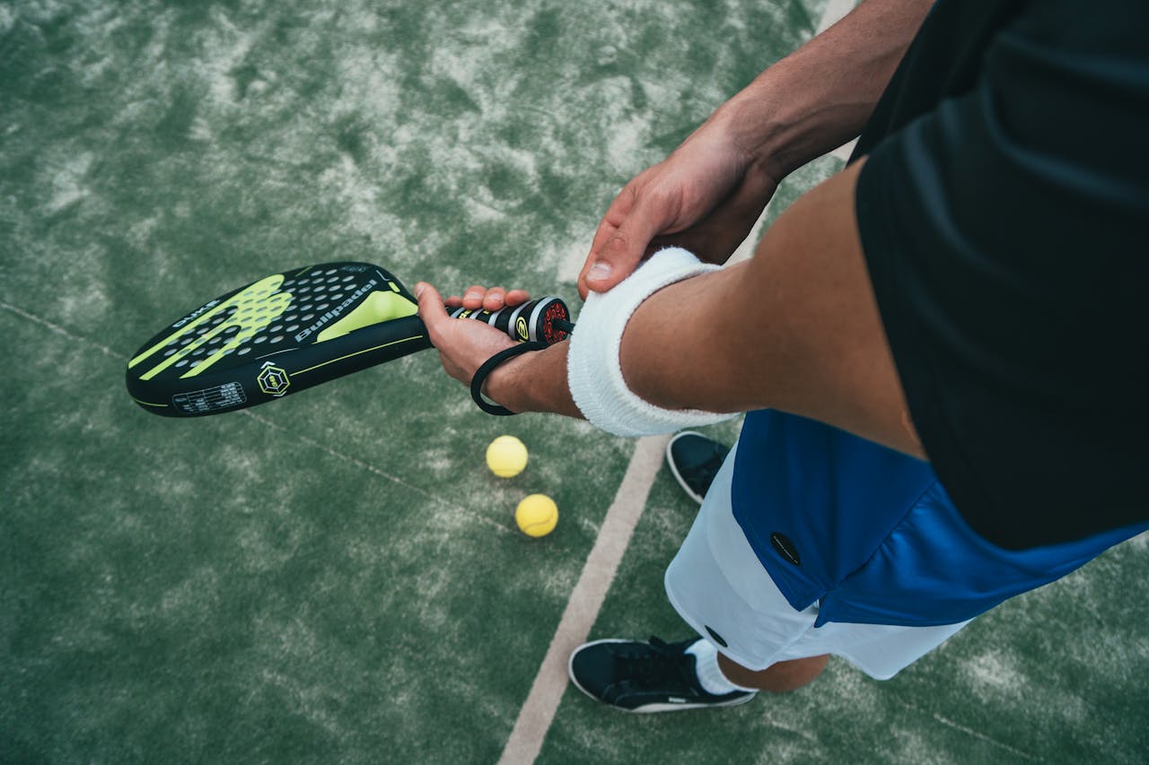 why-choose-us Close-up of a male padel player adjusting wristband on a court. Sports action focused.